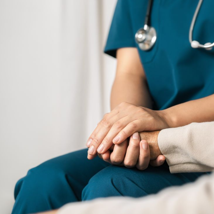Un professionnel de la santé tient la main d'un patient dans un environnement clinique calme.