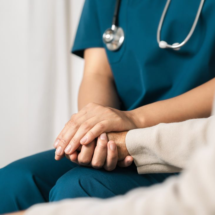 Un professionnel de la santé tient la main d'un patient dans un environnement clinique calme.