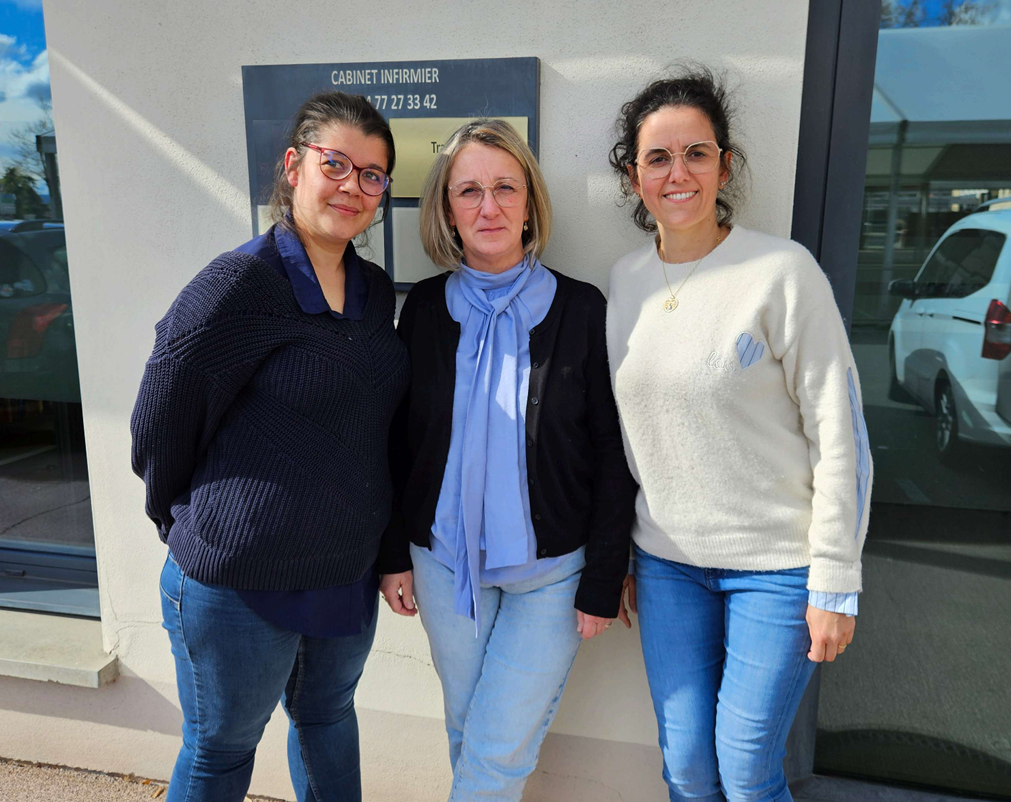 Trois personnes debout devant un bâtiment, souriant à l'objectif.