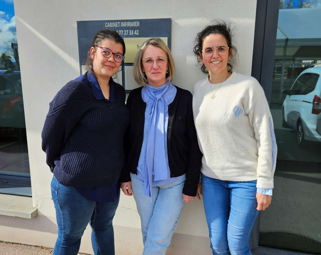Trois personnes debout devant un bâtiment, souriant à l'objectif.