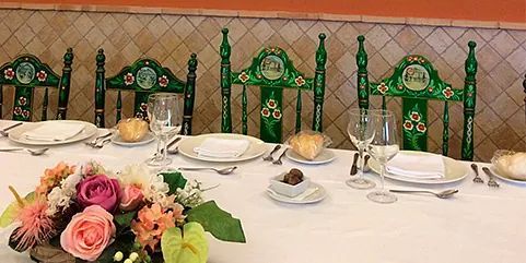 Una mesa con platos, cubiertos, copas de vino y flores sobre ella.