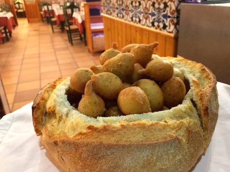 Un cuenco de pan lleno de comida frita sobre una mesa