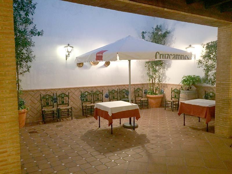 Un patio con mesas y sillas bajo una sombrilla que dice cruzamos