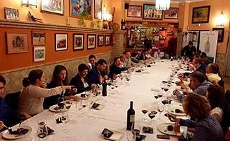 Un grupo de personas está sentado en una mesa larga en un restaurante.