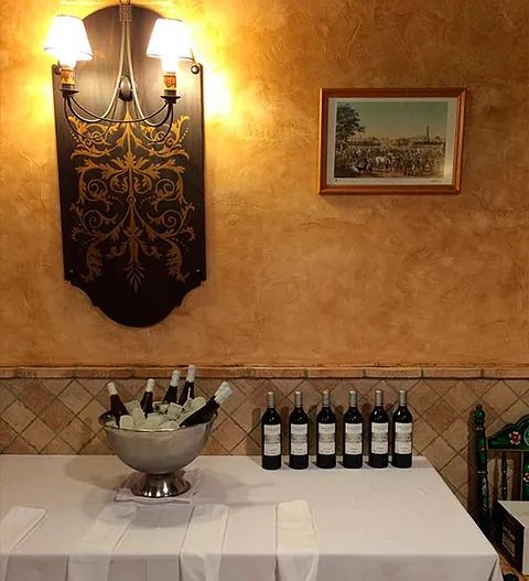 Una mesa con botellas de vino y un bol de hielo encima.