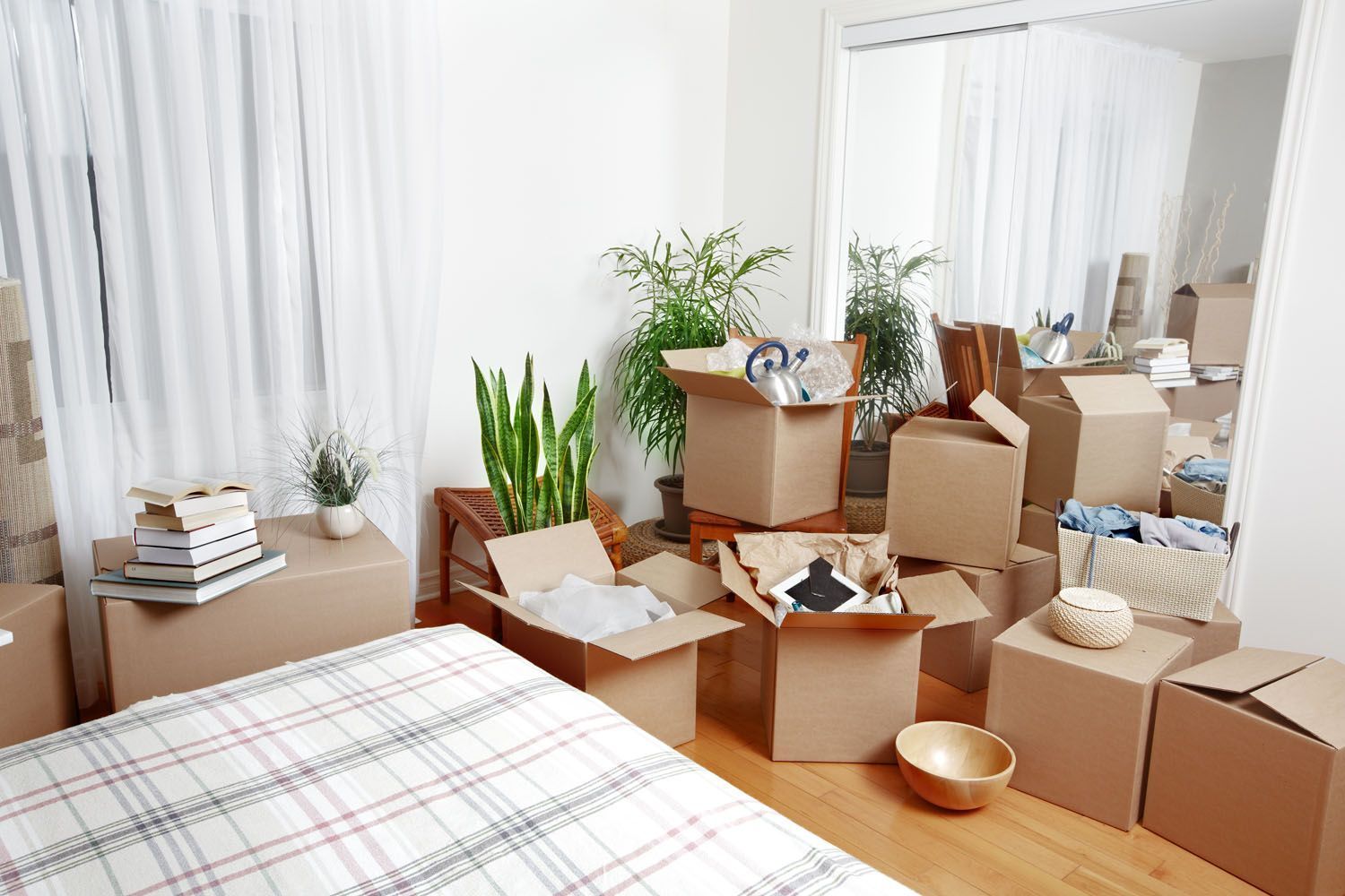 Ein Schlafzimmer voller Pappkartons und einem Bett.