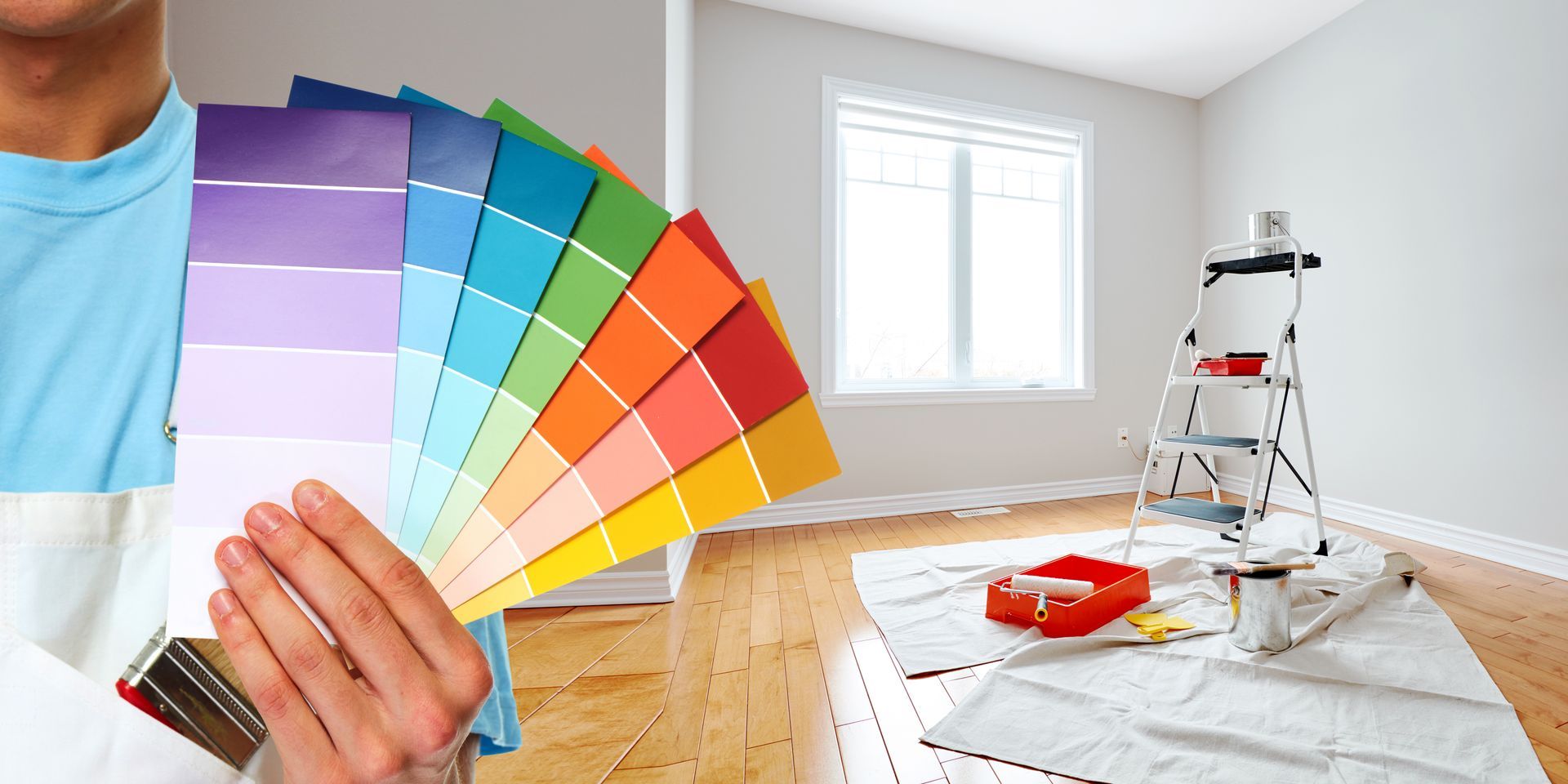 Nuancier tenu devant des murs blancs et un parquet couvert de protections blanches