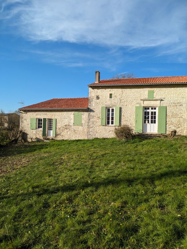 Maison avec des façades en pierre et des volets verts repeints
