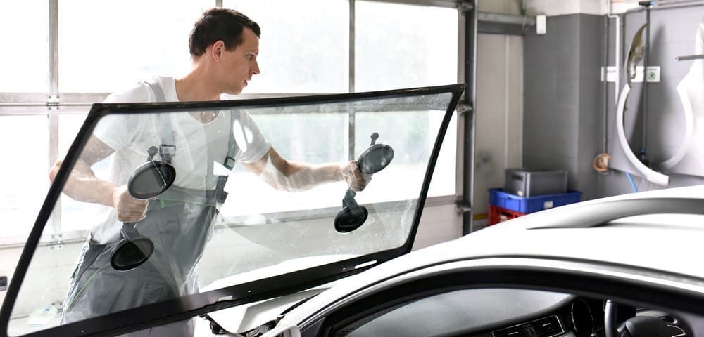 Ein Mann installiert eine neue Windschutzscheibe auf einem Auto | Gotthelf Garage AG