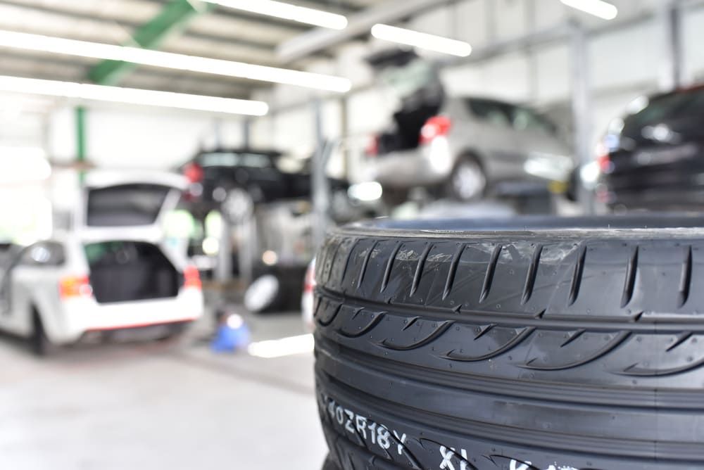 Ein Reifen steht in einer Garage mit Autos im Hintergrund | Gotthelf Garage AG