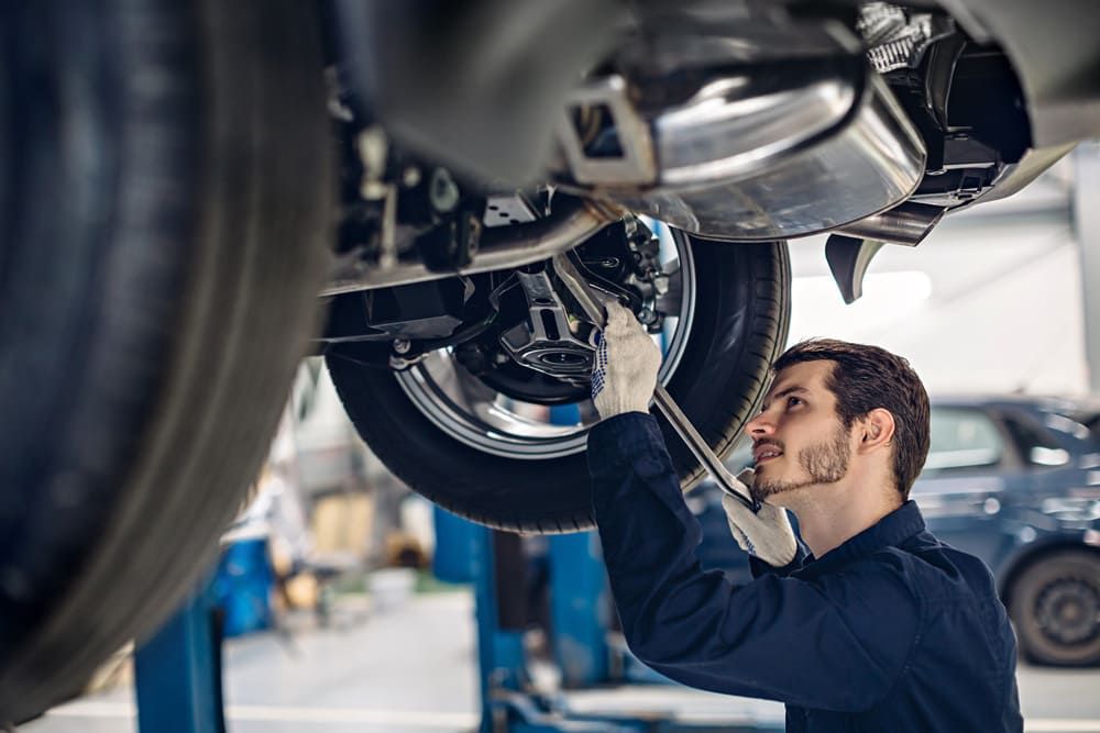 Ein Mechaniker arbeitet an der Unterseite eines Autos | Gotthelf Garage AG