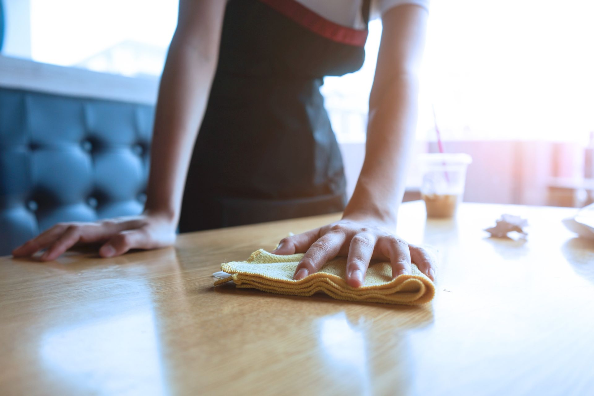 Una mujer está limpiando una mesa de madera con un paño.