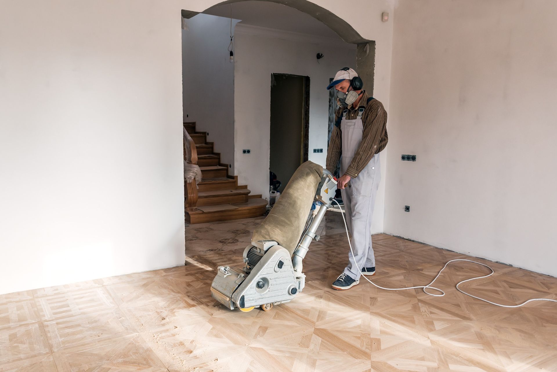 Un hombre está lijando un piso de madera con una máquina.