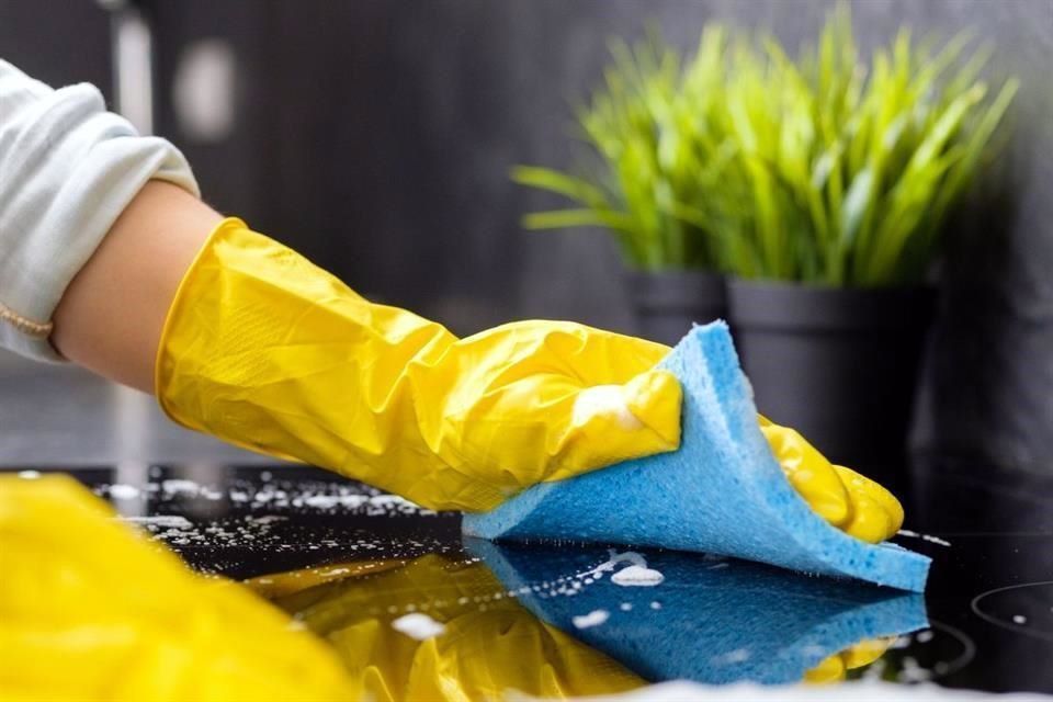 Una mujer está limpiando una mesa de madera con un paño.