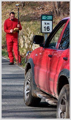 Un hombre está parado al lado de un camión rojo al costado de la carretera.