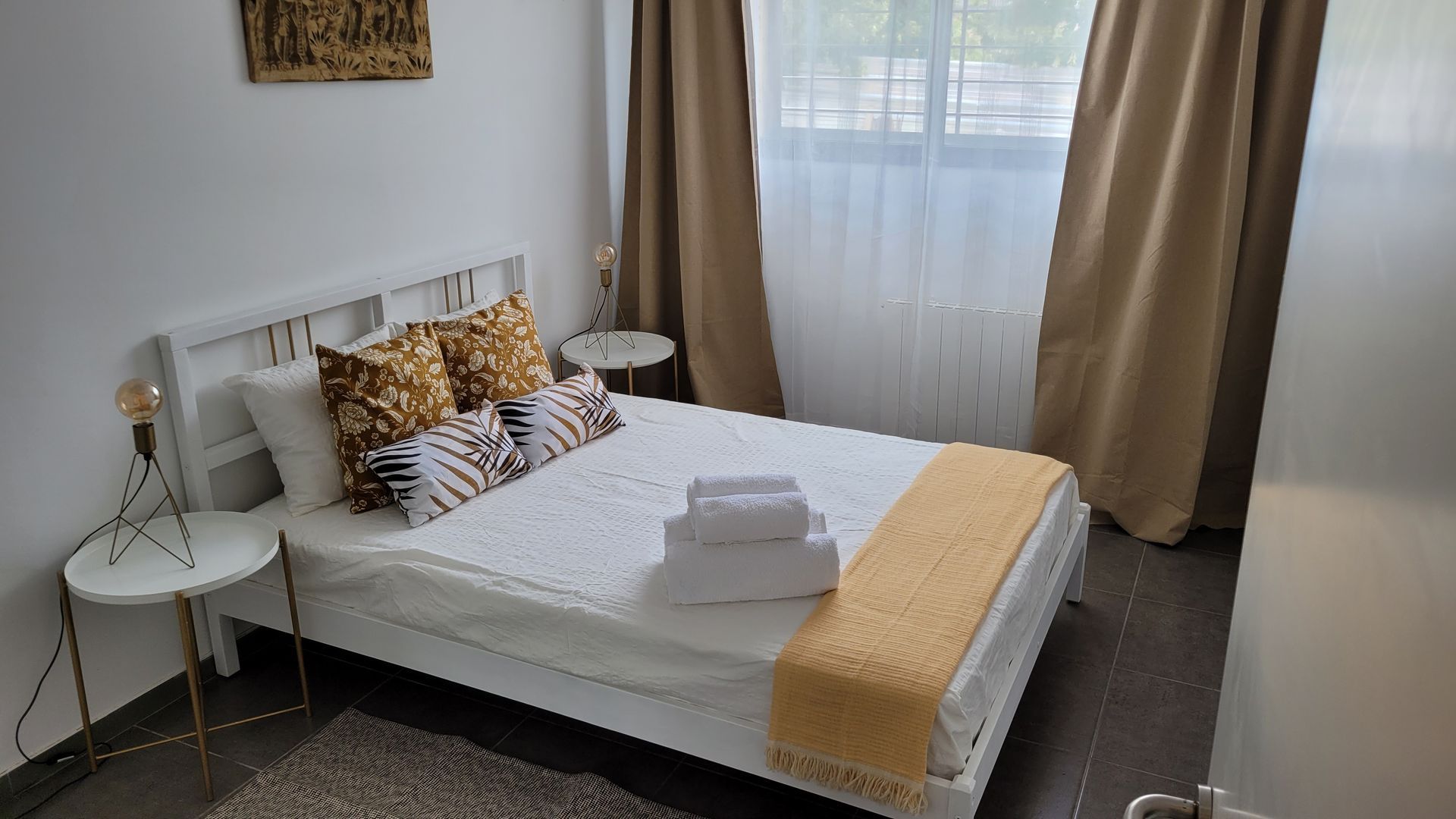 Un dormitorio con una cama, dos mesitas de noche y una ventana.