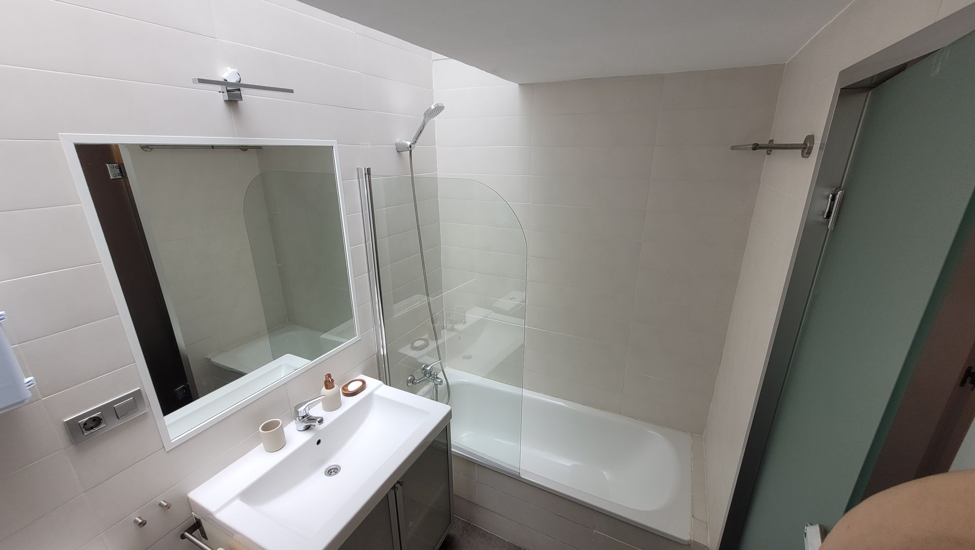 Un baño con lavabo, bañera y espejo.