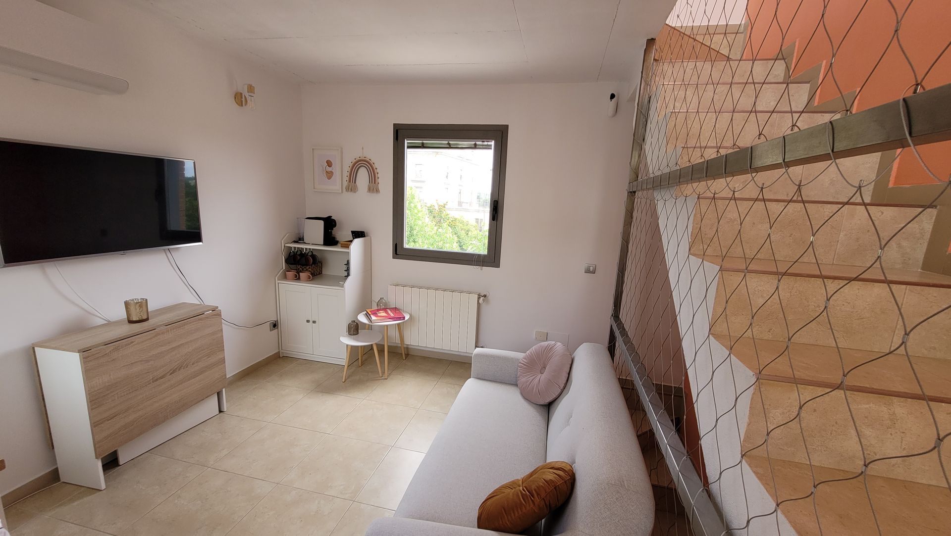 Una sala de estar con sofá, televisión y escaleras.