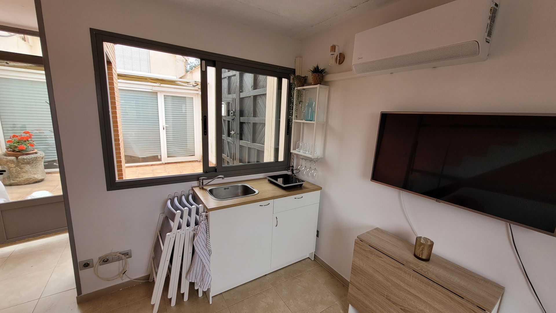 Una cocina con fregadero, mesa y televisión.