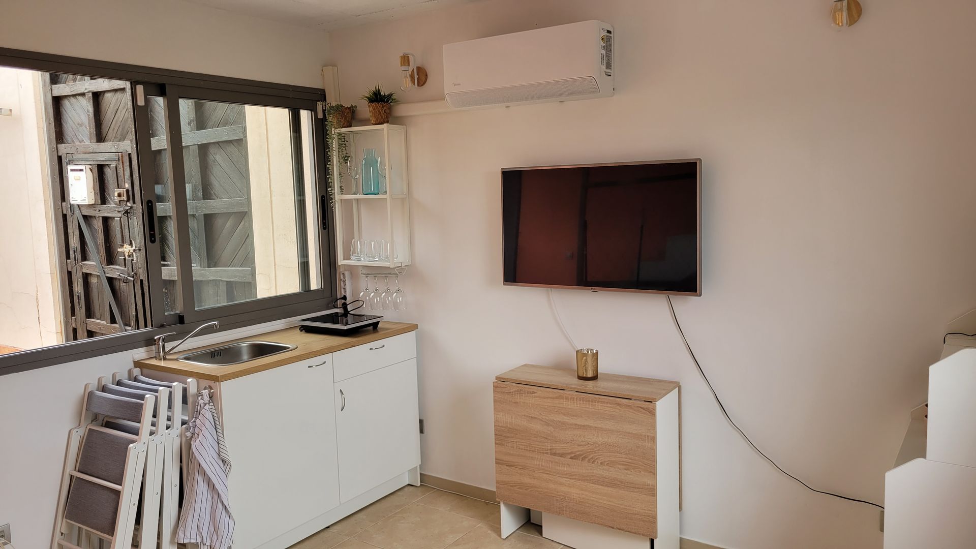 Una sala de estar con TV de pantalla plana y lavabo.