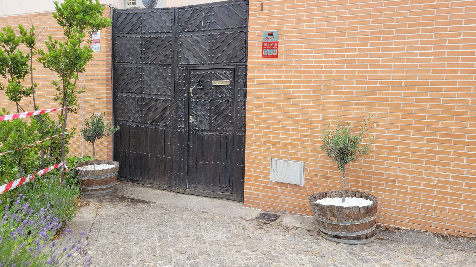 Un edificio de ladrillo con una puerta negra y plantas en macetas delante.