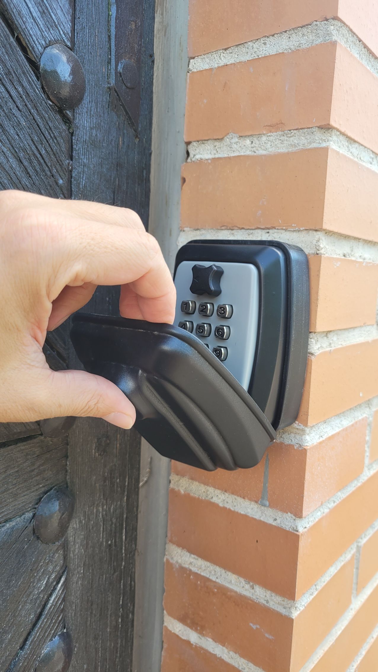 Una persona está abriendo una puerta que tiene una caja fuerte con llave adjunta.
