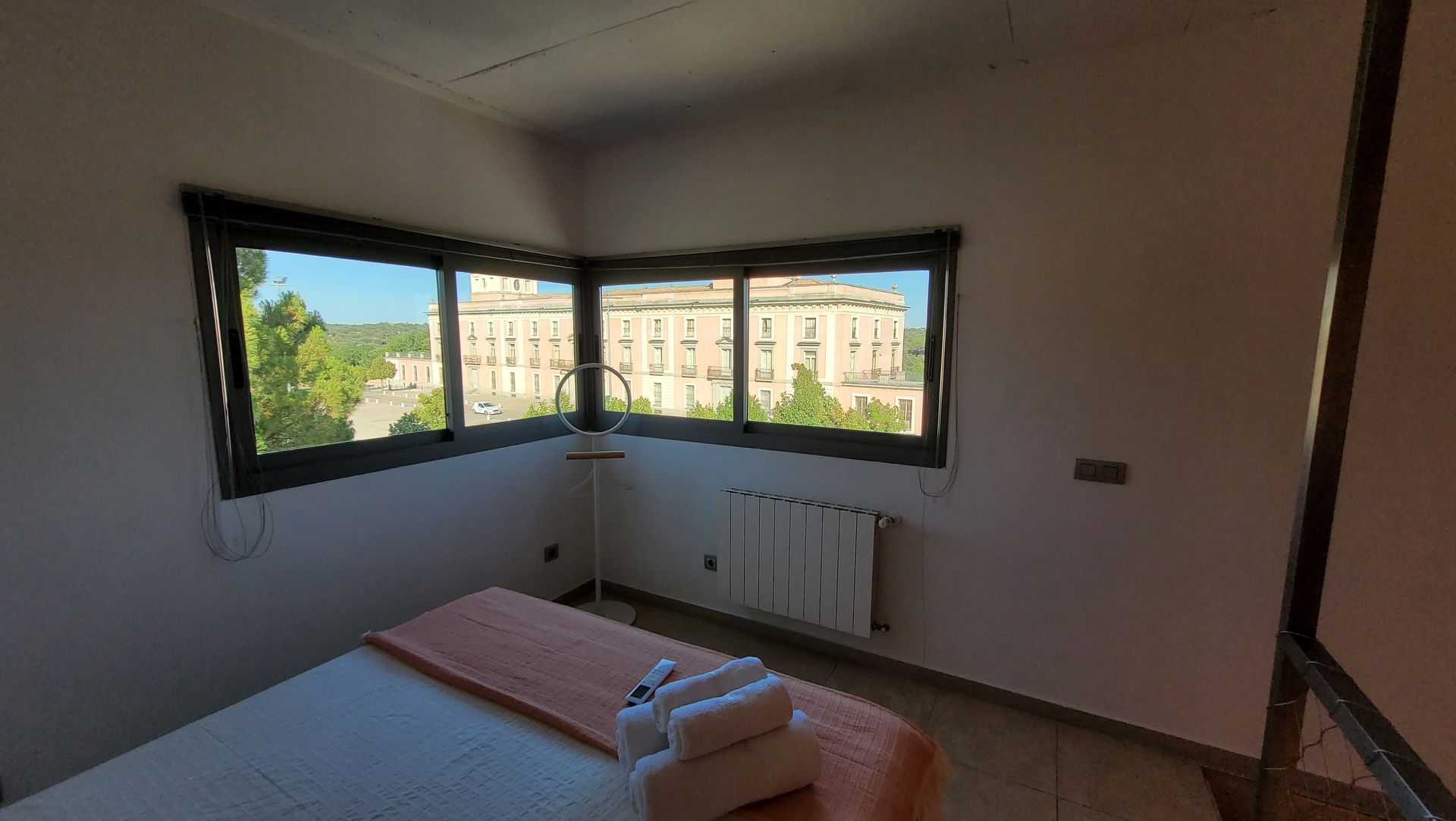 Un dormitorio con una gran ventana y una cama.