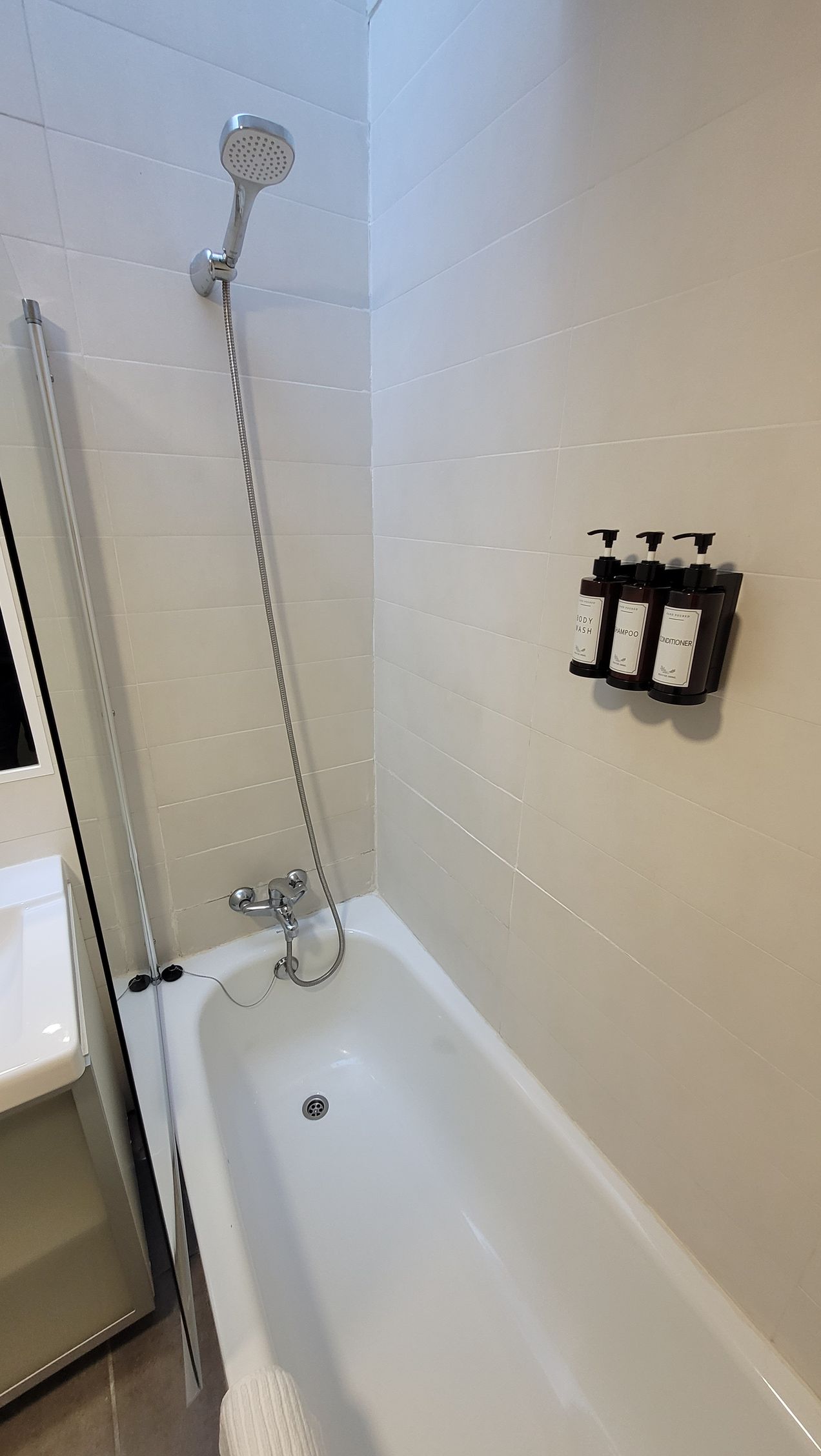 Un baño con bañera, ducha y dispensadores de jabón.