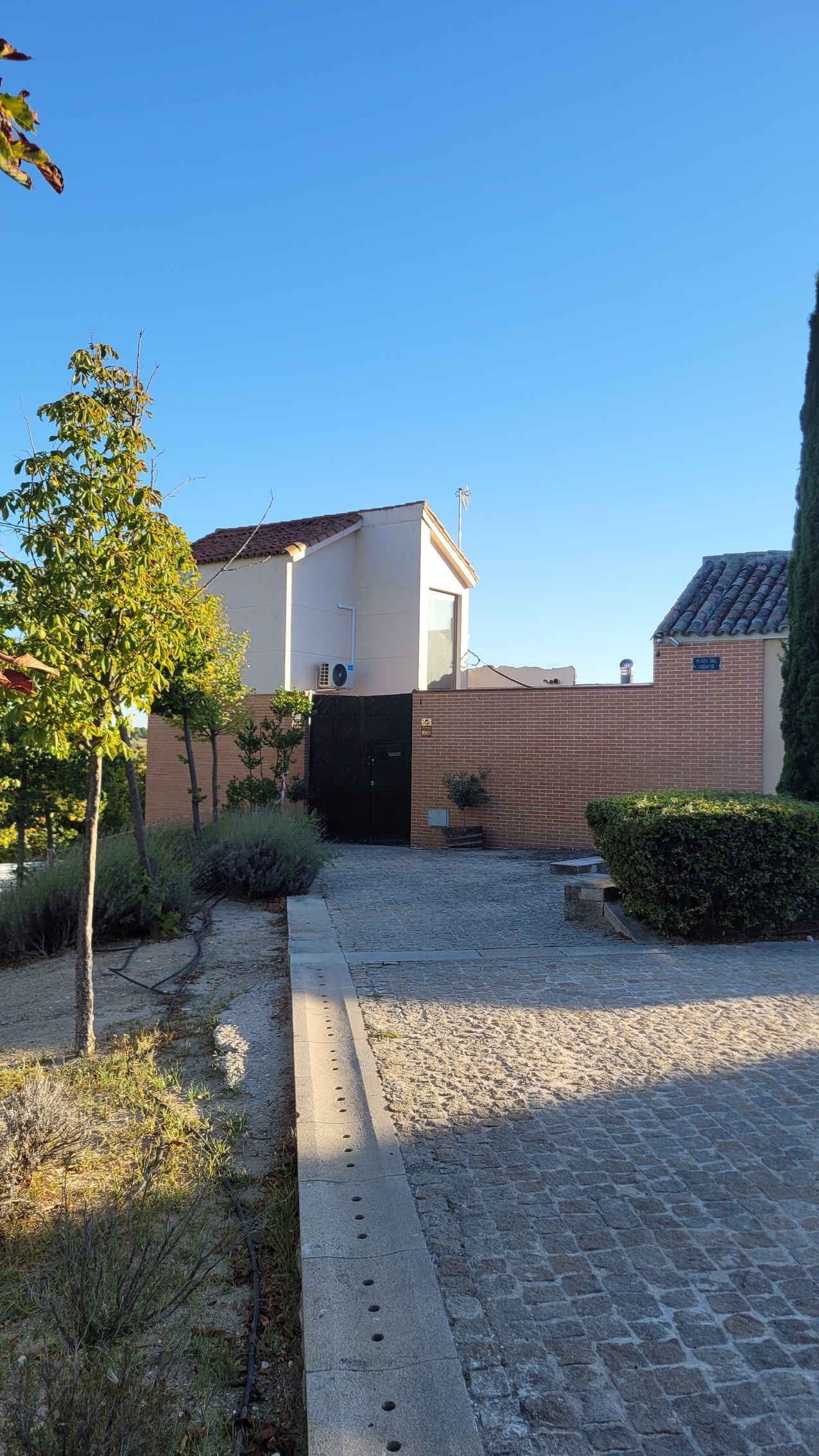Un camino adoquinado que conduce a una casa con un cielo azul al fondo.