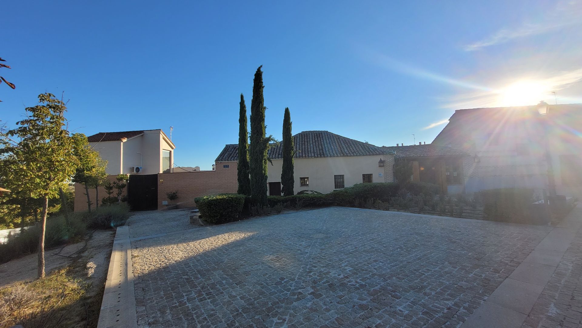 Un camino de grava que conduce a una casa con árboles delante de ella.