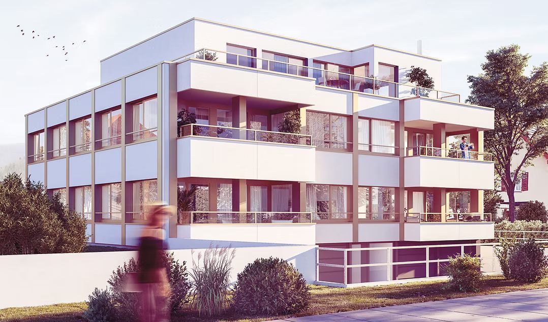 Ein modernes, dreistöckiges weißes Wohnhaus mit Balkonen und großen Fenstern, umgeben von Bäumen und Grünanlagen.