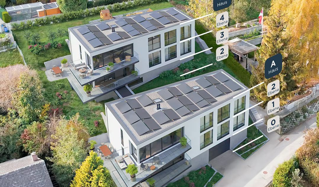 Luftaufnahme von zwei modernen, mehrstöckigen Häusern mit Solarpaneelen auf ihren Flachdächern in einem üppig grünen Wohngebiet.