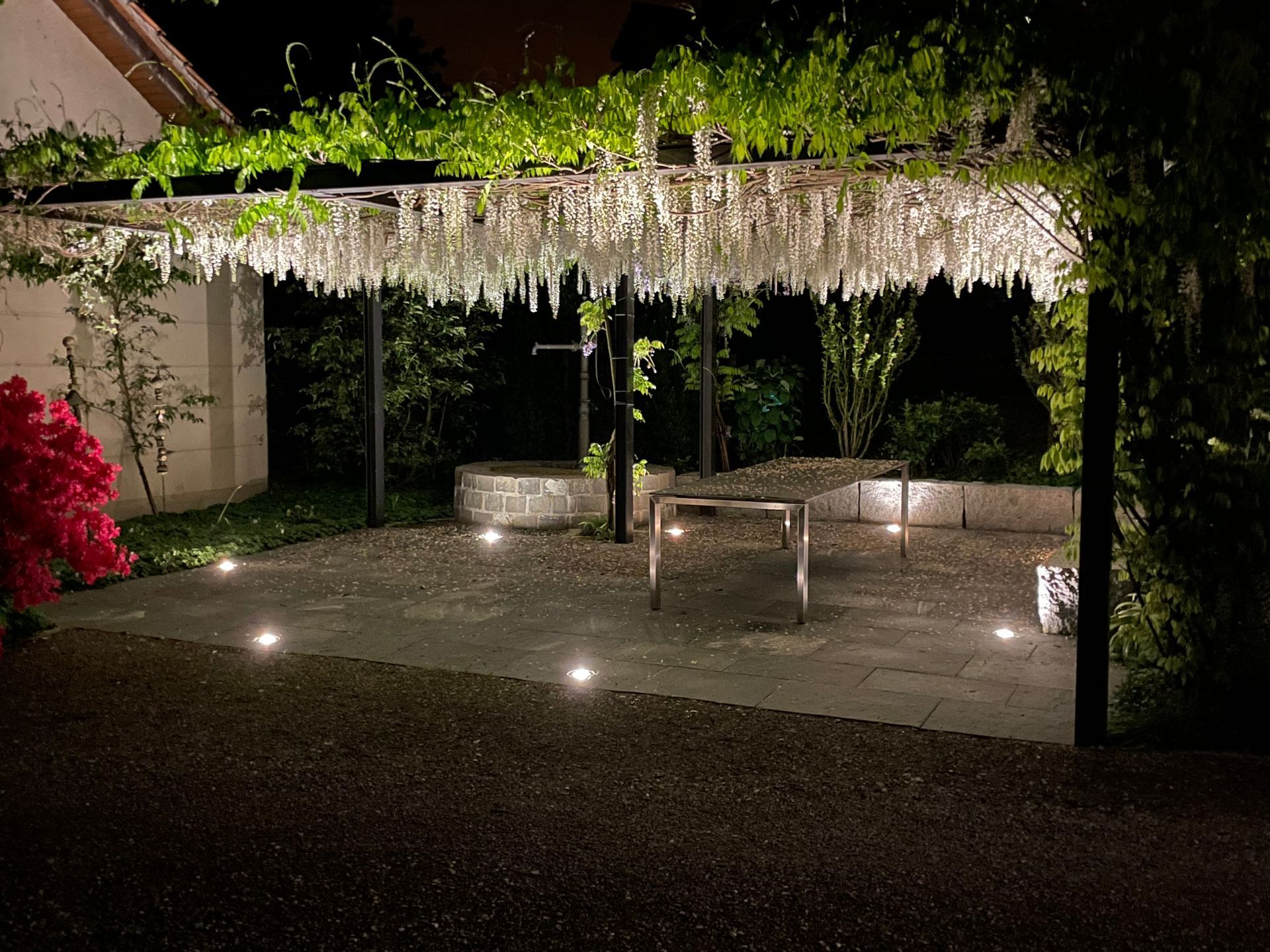 Eine Pergola ist nachts in einem Garten beleuchtet