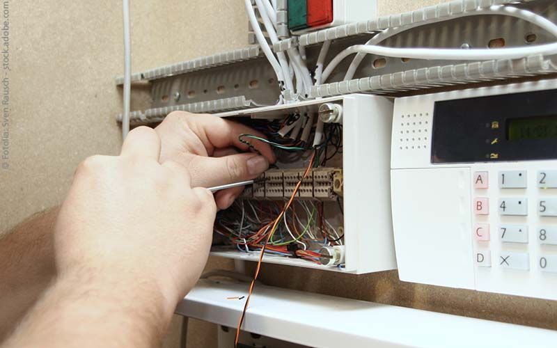 Die Hände einer Person verbinden Drähte in einer Schalttafel