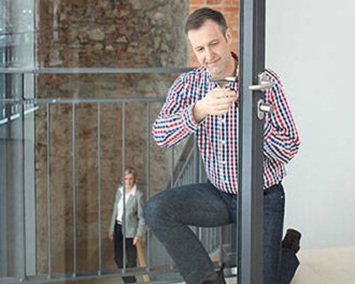Mann kniet vor der Tür und schließt sie auf, Frau geht die Treppe hinauf.