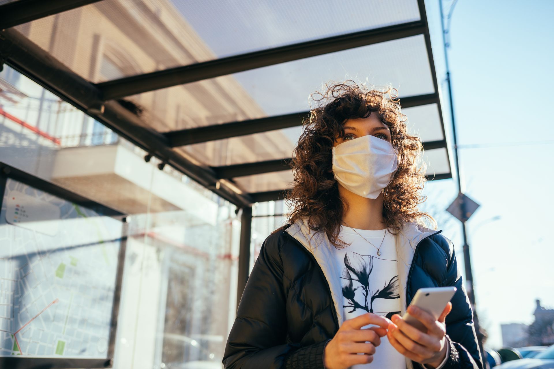 Une femme portant un masque avec son téléphone à la main