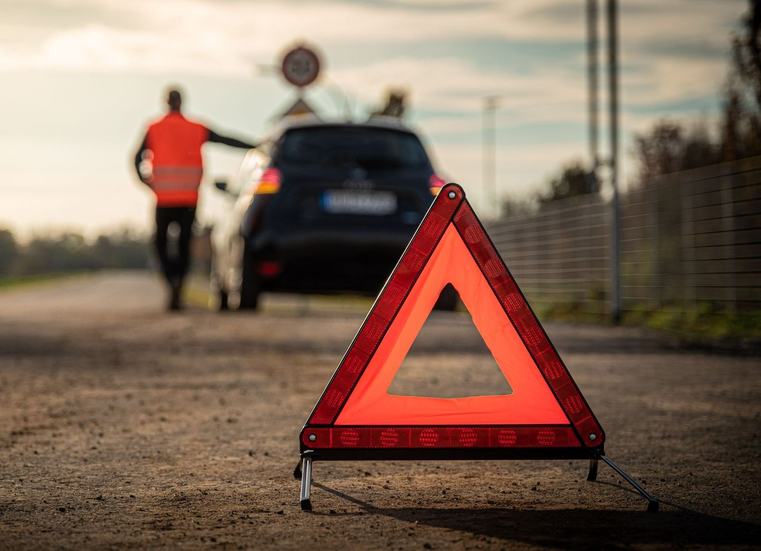 Un triangle de sécurité sur une route devant une voiture arrêtée