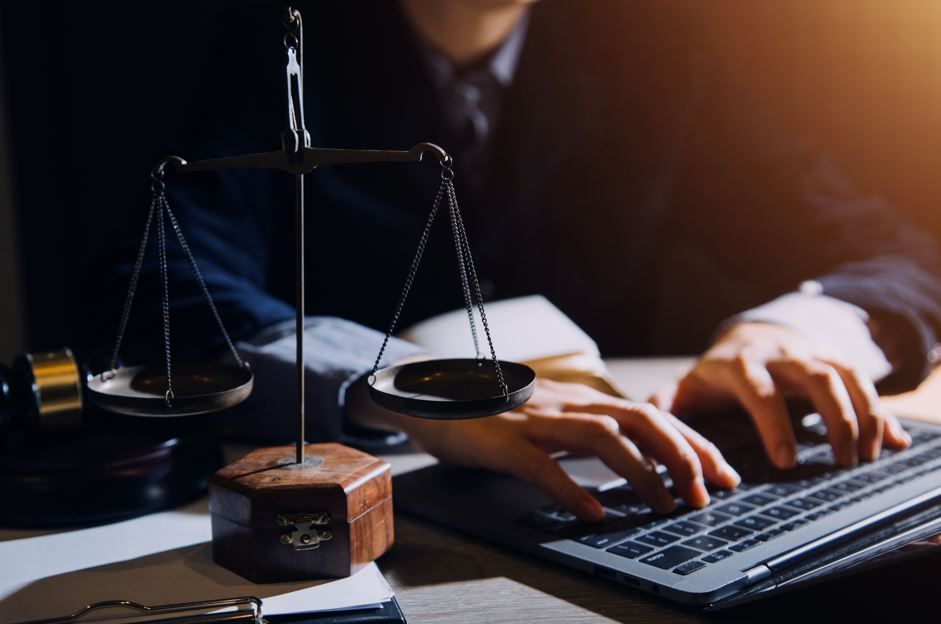 Balanza de la justicia, mazo y una persona escribiendo