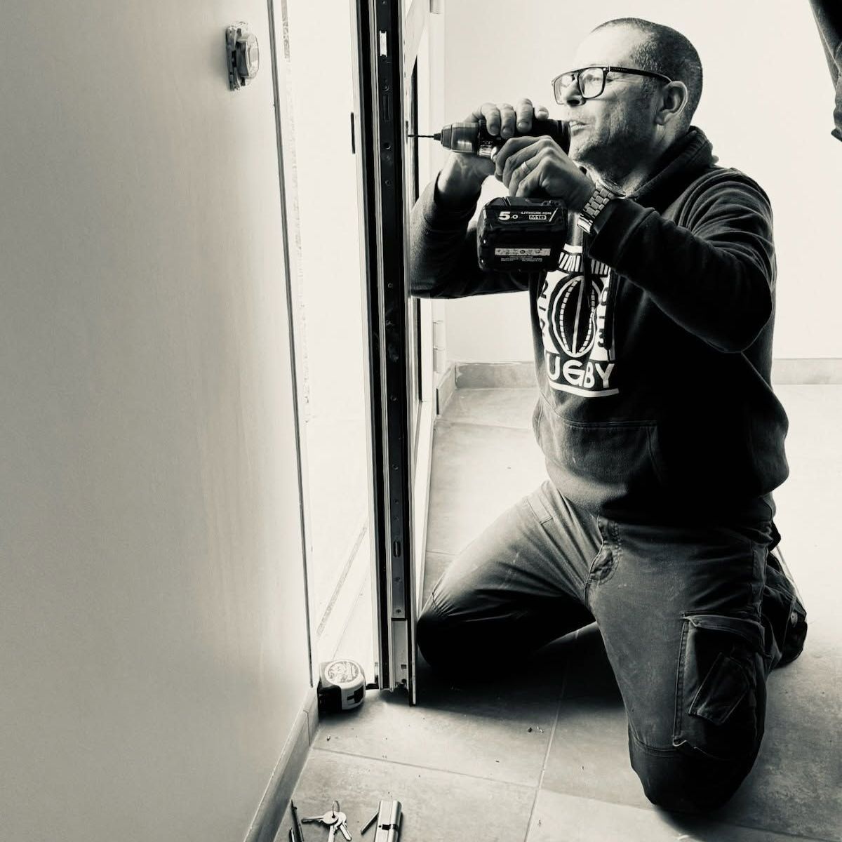 Honne en train d'utiliser une perçeuse sur une porte