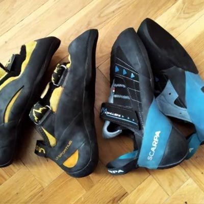 Un par de zapatos de escalada Scarpa sobre un suelo de madera.