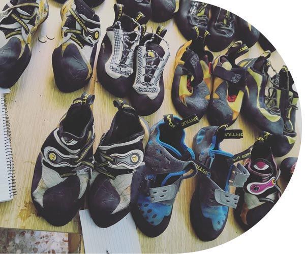 Un montón de zapatos de escalada están alineados sobre una mesa.