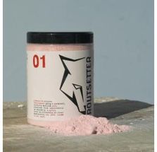 Un frasco de polvo rosa está sobre una mesa al lado de una pila de polvo rosa.