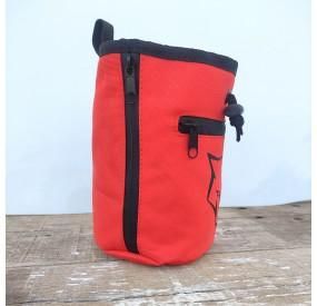 Una bolsa roja con una cremallera negra está sobre una mesa de madera.