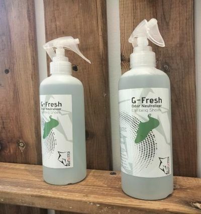 Hay dos botellas de spray de g-fresh sobre un estante de madera.