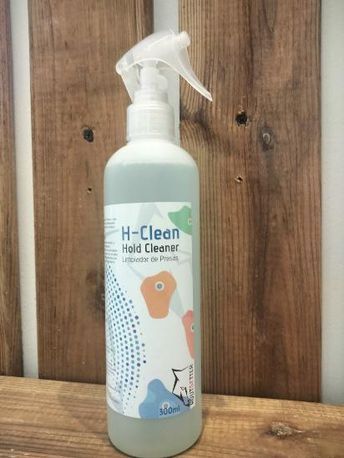 Una botella de limpiador de manos H-Clean está sobre una mesa de madera.