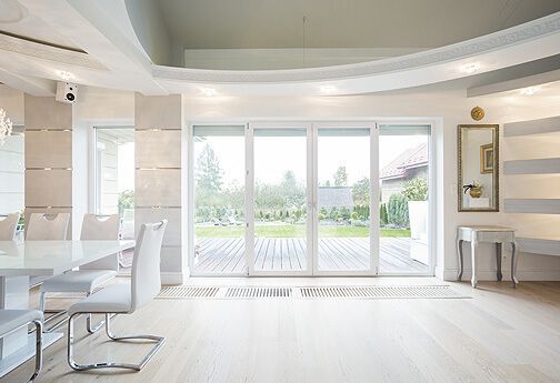 Ein großes Esszimmer mit Tisch und Stühlen und Glasschiebetüren, die auf eine Terrasse führen.