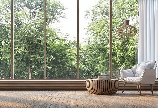 Ein Wohnzimmer mit einem großen Fenster mit Blick auf einen Wald.