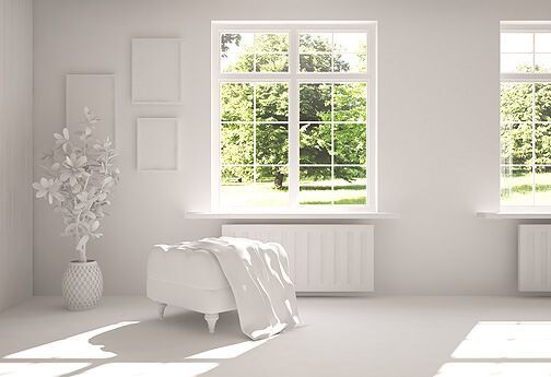 Ein weißer Raum mit einem Bett, einem Ottomanen und einem Fenster.