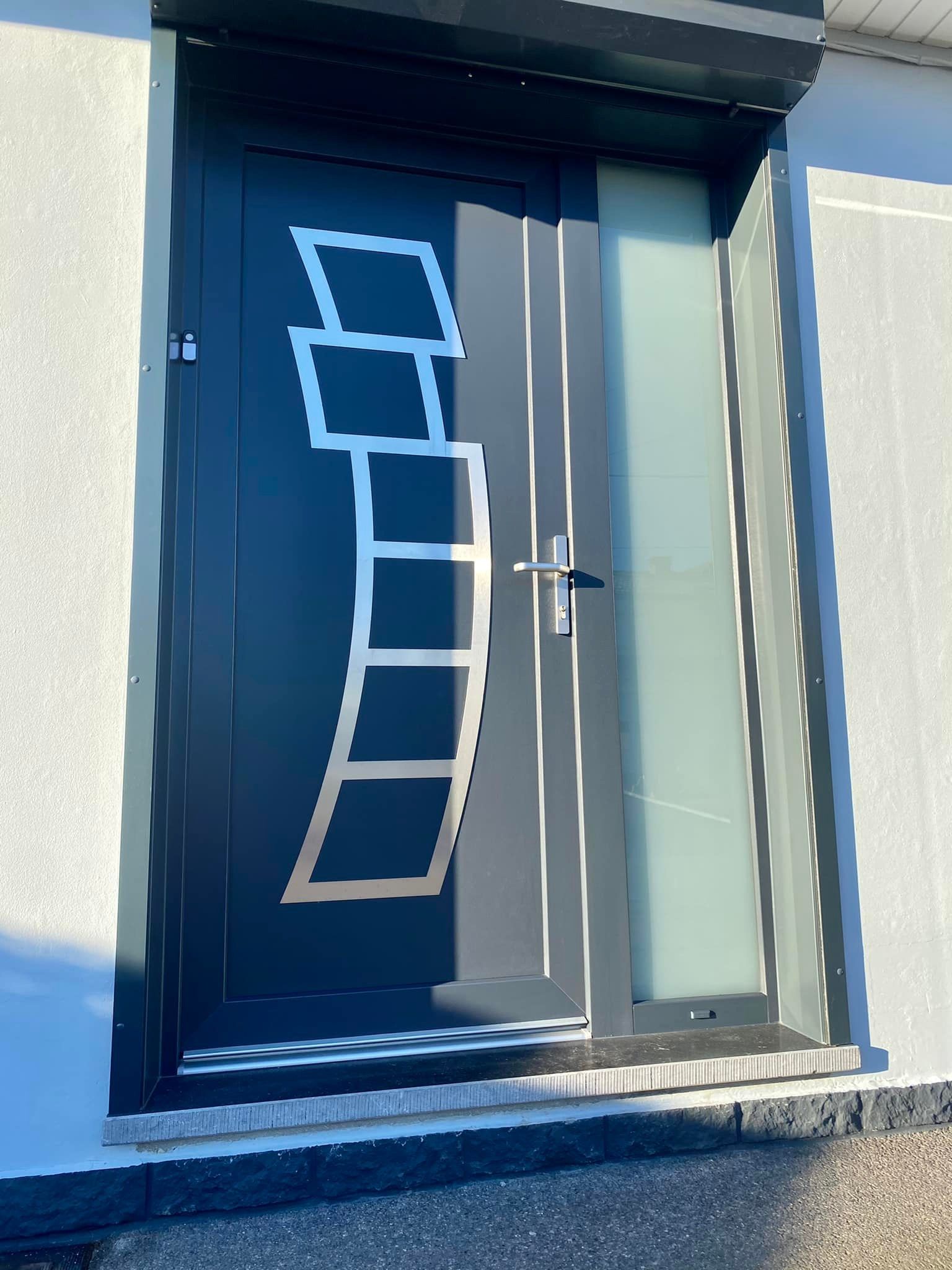 Porte bleue ornée d'un motif blanc en forme d'échelle, encastrée dans un mur extérieur moderne.