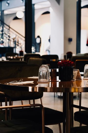 Tables de café inoccupées, avec des chaises, de la verrerie et un bol de baies, dans l’intérieur d’un restaurant à l’éclairage tamisé